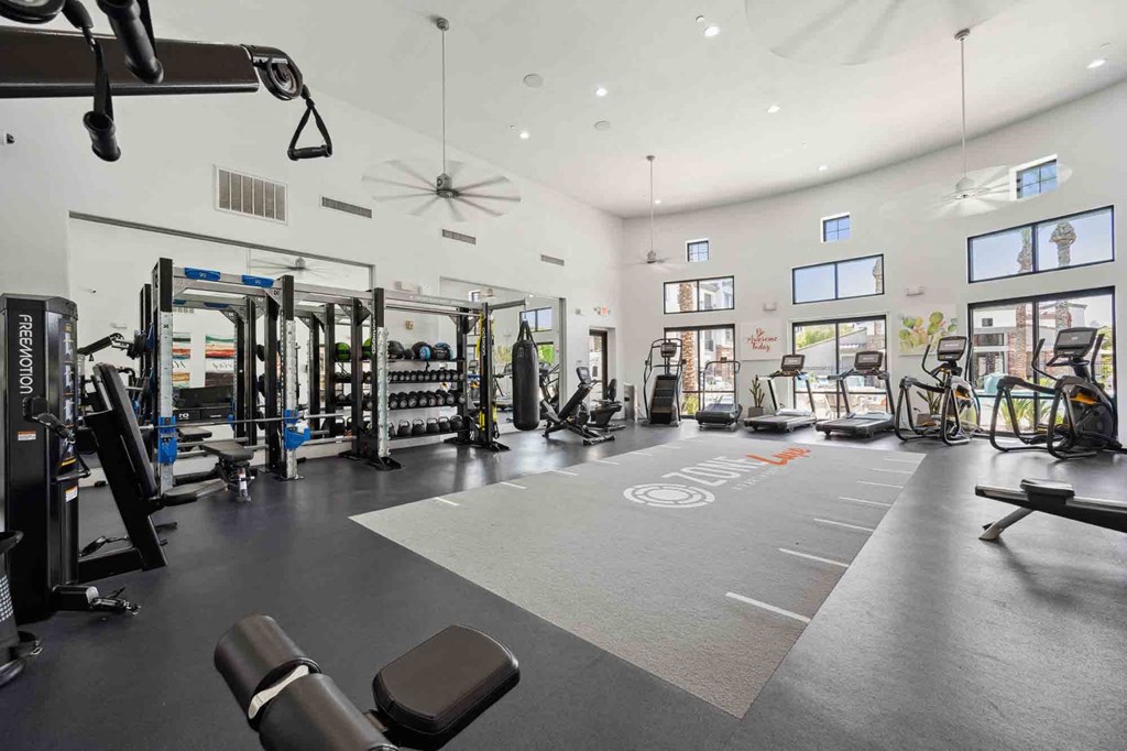 a spacious fitness center with cardio equipment and weights