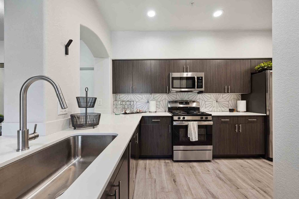 a kitchen with white countertops and dark wood cabinets