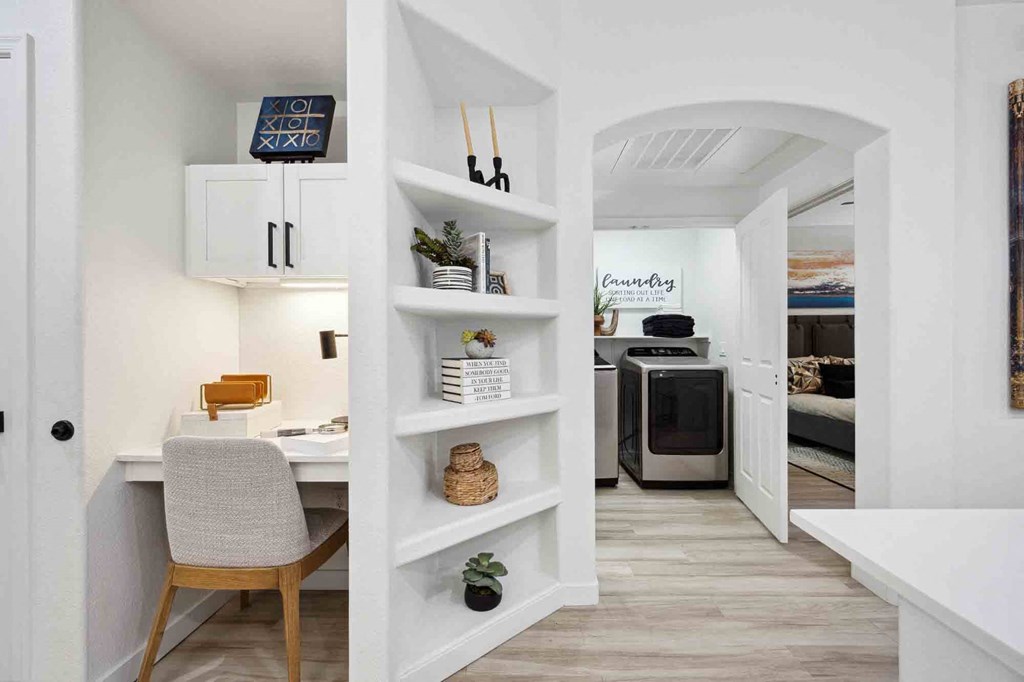 a home office with a white desk and chair next to a white bookshelf with a