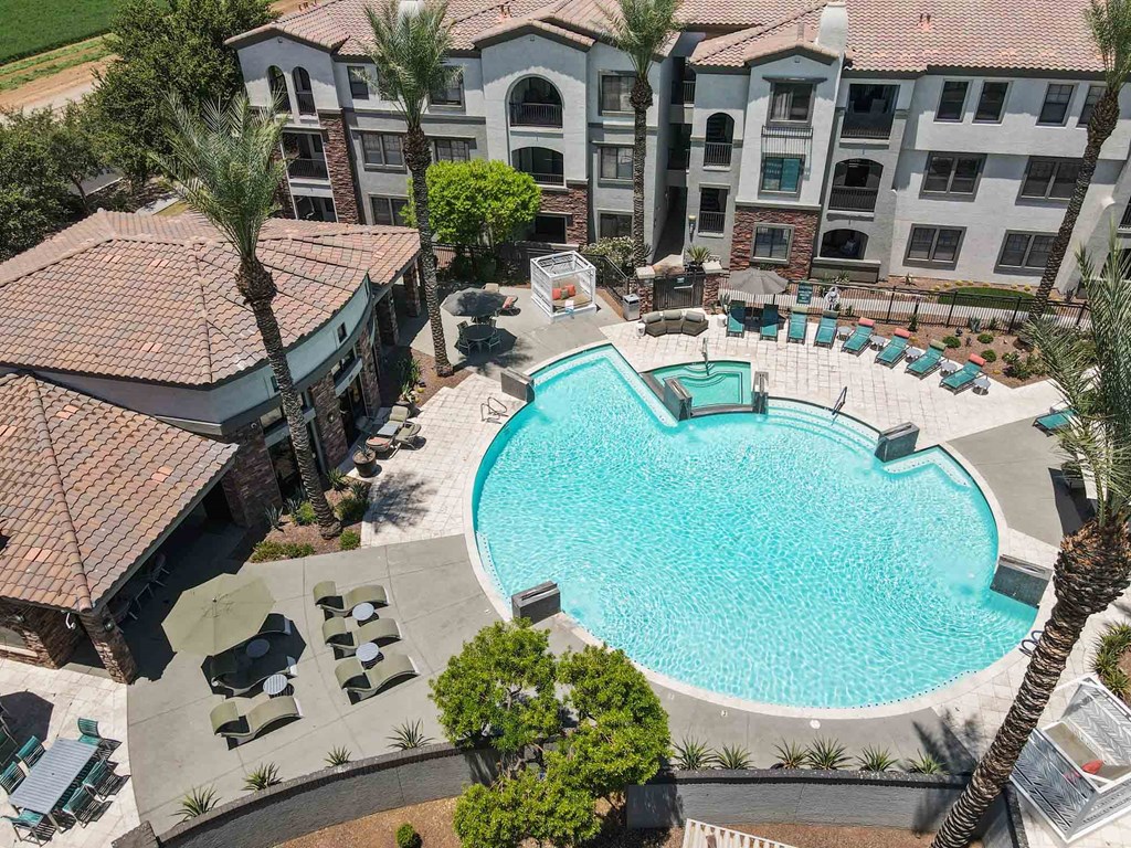 an aerial view of a large swimming pool with lounge chairs and umbrellas in front of