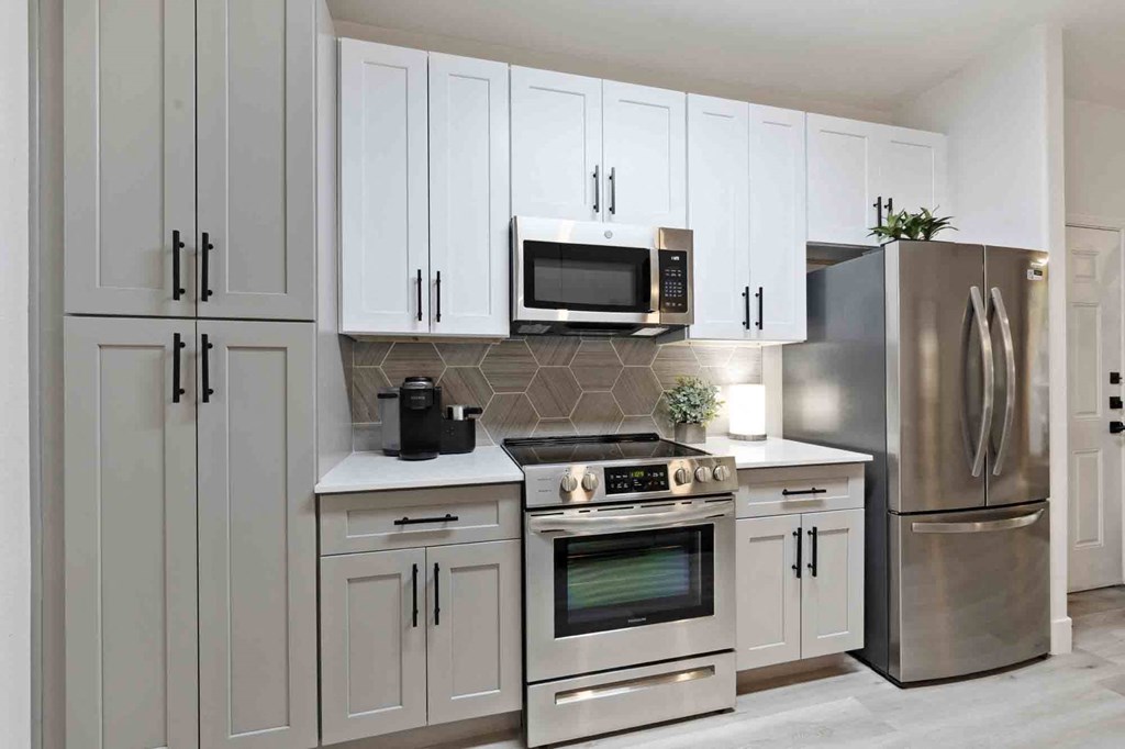A kitchen with gray and white cabinets and stainless appliances at Zone Westgate, townhomes for rent in Glendale, AZ.