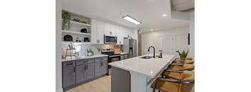 A modern kitchen with a white countertop and grey cabinets.