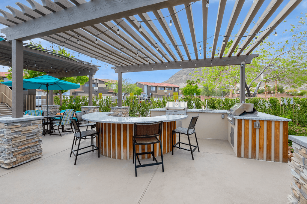 a patio with a bar and chairs and a pergola