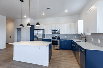 a large kitchen with blue and white cabinets and a white counter top