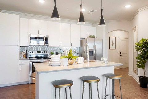 A kitchen with a white counter and bar stools.