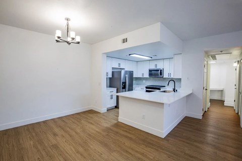 A kitchen with white cabinets and a wooden floor.