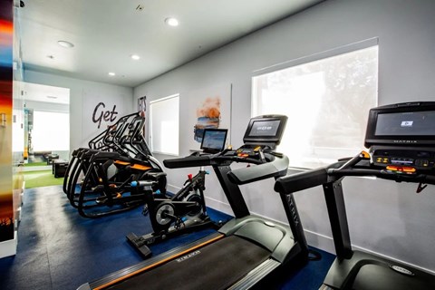 A gym with a treadmill, exercise bike, and rowing machine.