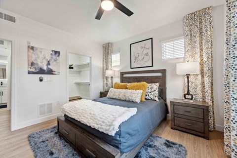 A bedroom with a bed, nightstand, and a ceiling fan.