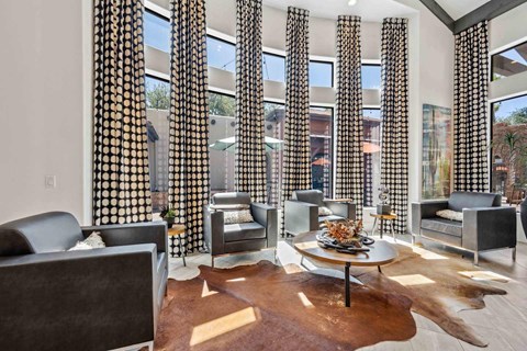 A living room with a cowhide rug and a glass table with a vase of flowers on it.
