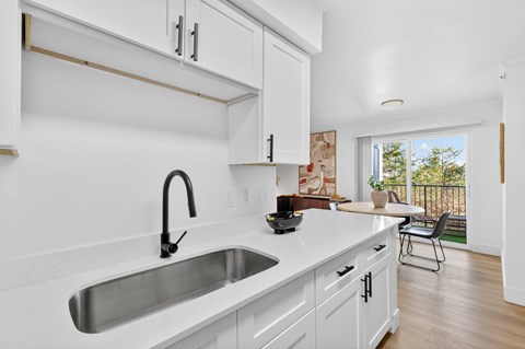 A kitchen with white cabinets and a stainless steel sink.