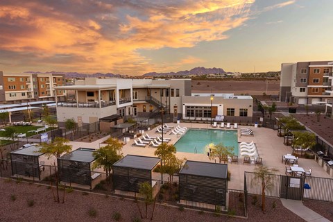 A resort with a pool and a sunset in the background.
