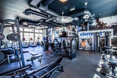 A gym with a variety of equipment including treadmills, weights, and exercise machines.