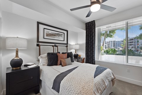 a bedroom with a bed and a ceiling fan and a window