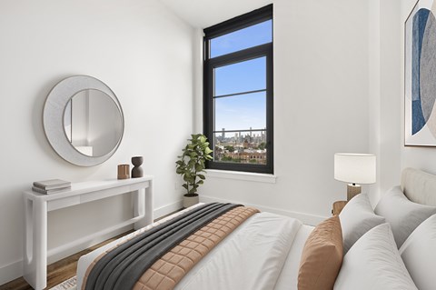 A bedroom with a large bed and a window overlooking a cityscape.