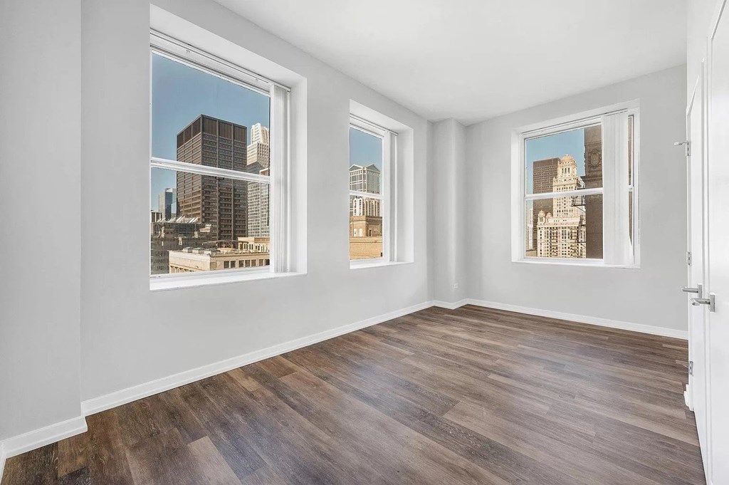 a living room with a hard wood floor and three windows