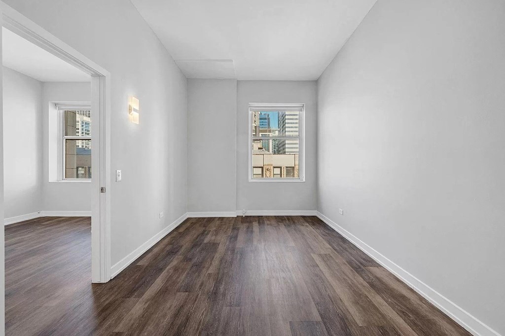 an empty living room with wood floors and a window