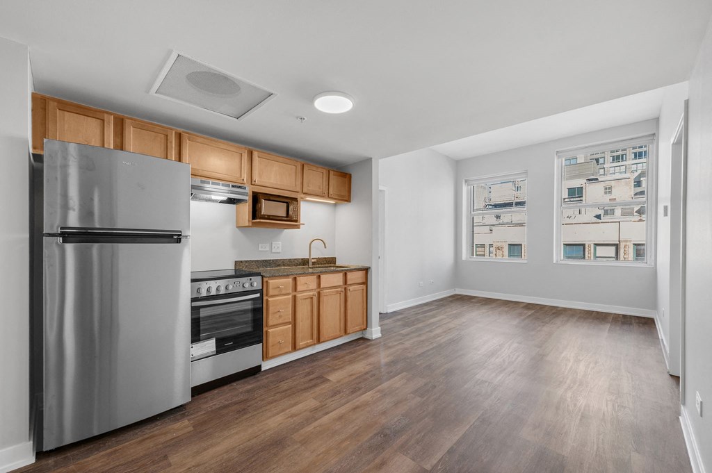 an empty kitchen with stainless steel appliances and wooden cabinets