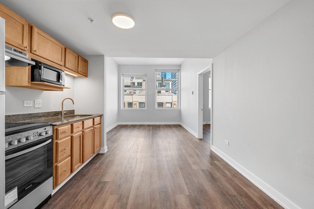 an empty kitchen and living room with wood flooring and a window