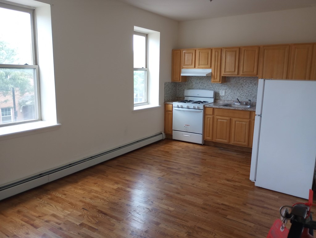 A kitchen with wooden floors and white appliances.
