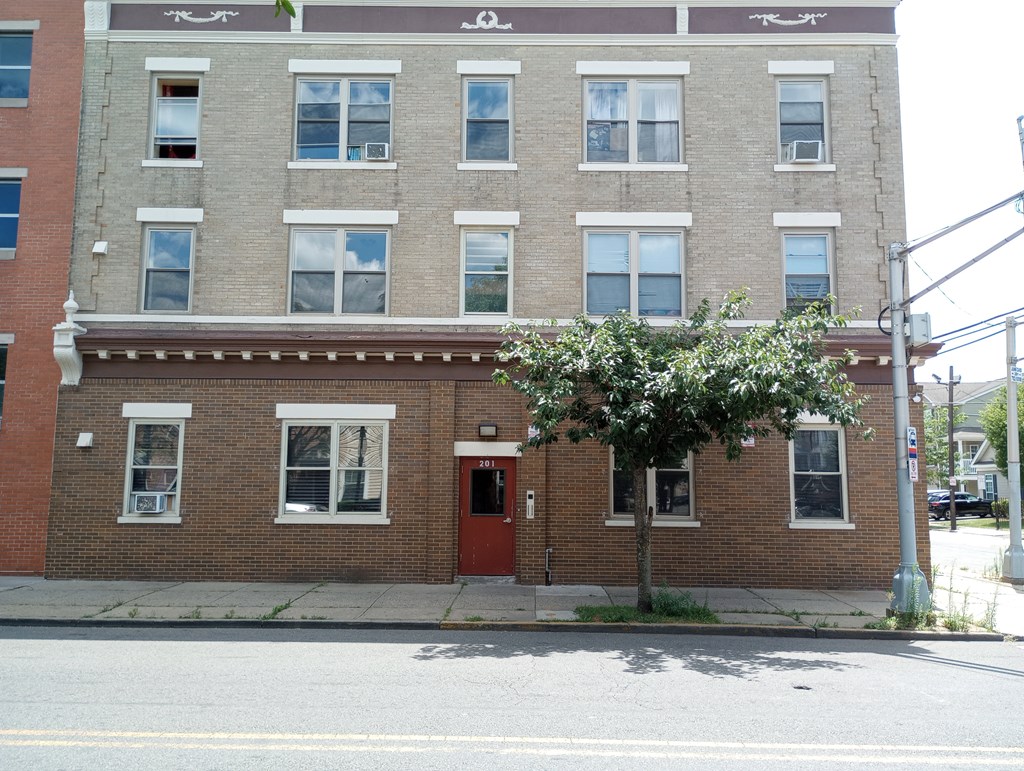 A red brick building with a tree in front of it.