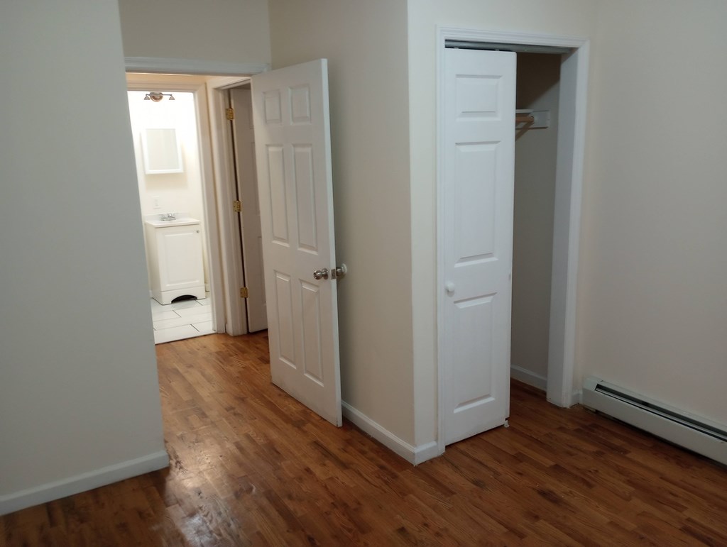 A room with a white door and a wooden floor.