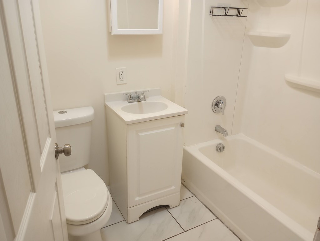 A white bathroom with a toilet, sink, and bathtub.