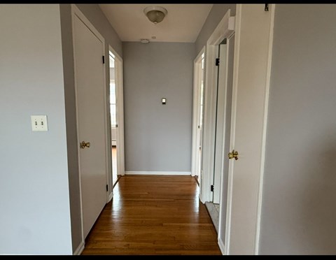 A long hallway with white walls and wood floors.