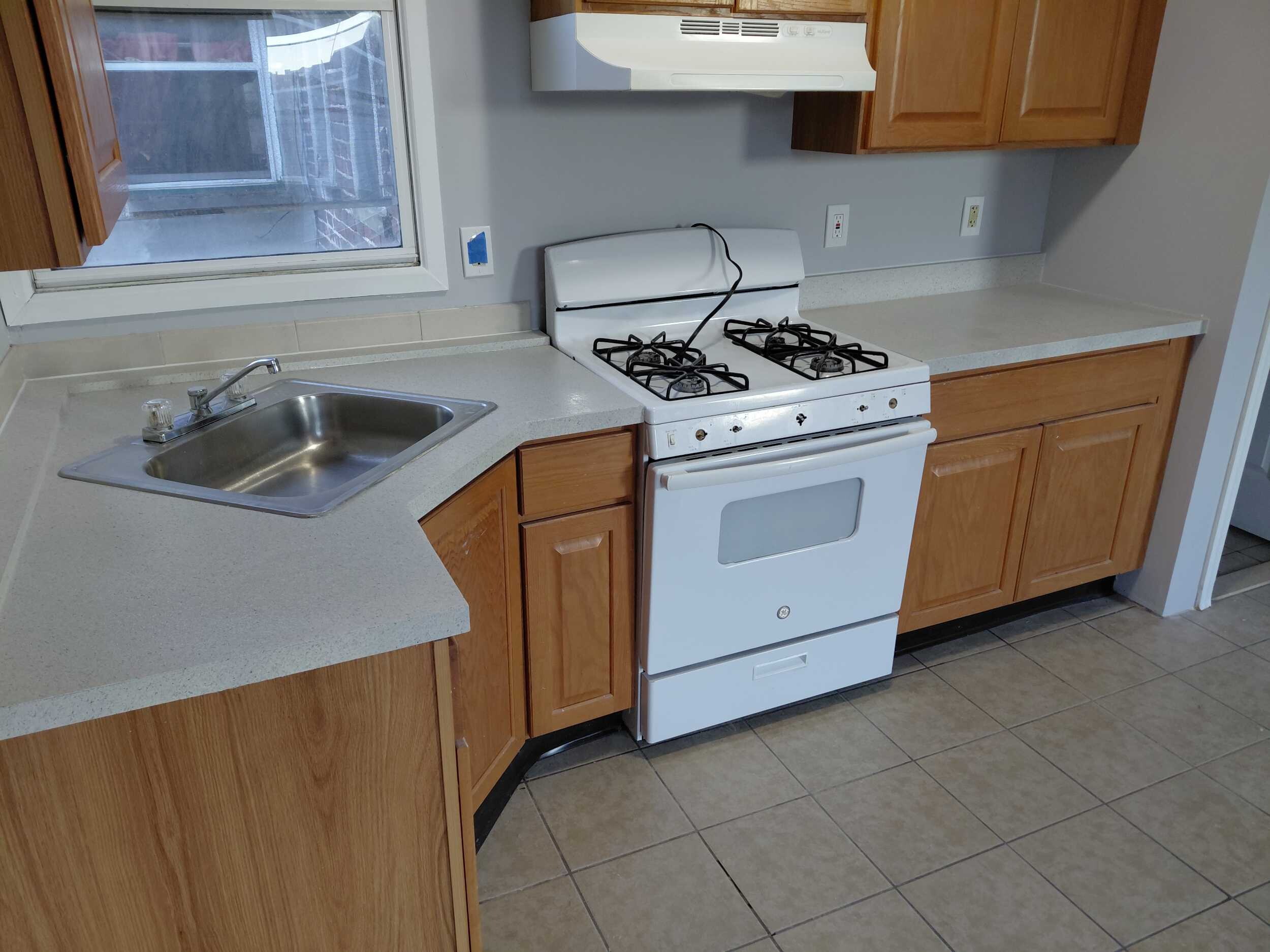 A white stove is in a kitchen with wooden cabinets.