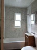 A white toilet is in a bathroom with a tub, sink and mirror.