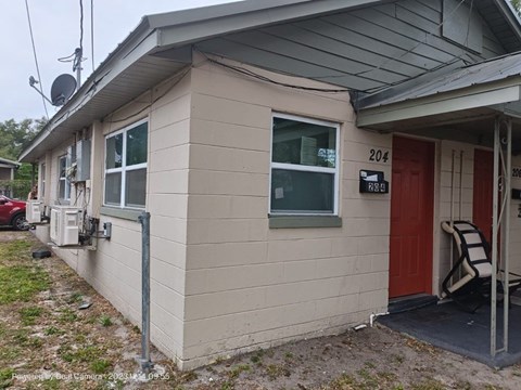 A small house with a red door and a satellite dish on the roof.