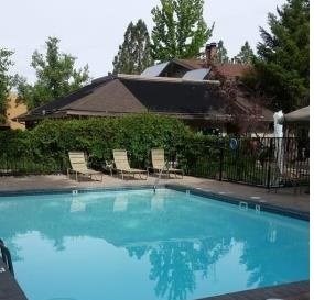 A pool in a backyard with a house and trees in the background.