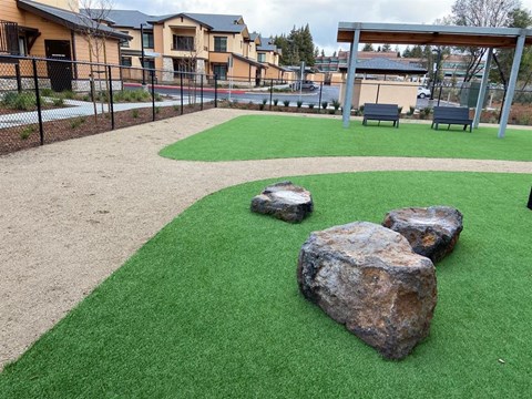 A playground with a green surface and rocks.