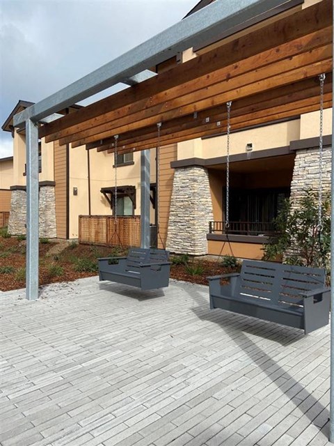 Two grey benches are placed on a patio in front of a building.