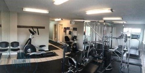 A gym with a variety of equipment including treadmills, weights, and exercise machines.