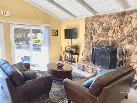A living room with a stone wall and a fireplace.