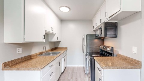 A kitchen with white cabinets and a granite countertop.