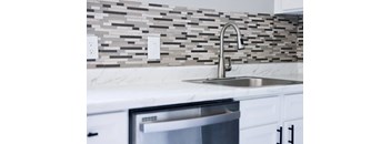 A modern kitchen with a marble countertop and a stainless steel sink.