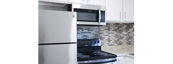 A modern kitchen with a stainless steel refrigerator, microwave, and stove.