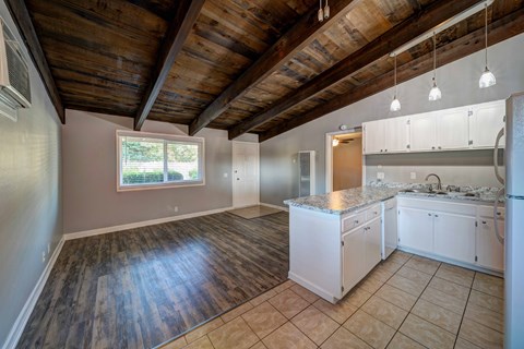 A kitchen with white cabinets and a wooden ceiling.