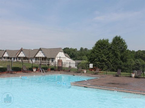 A pool with a fence and a building in the background.