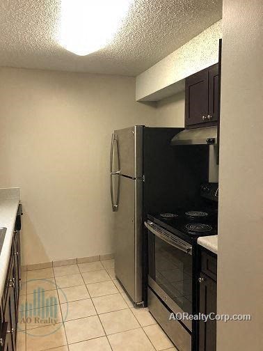 A small kitchen with a black refrigerator and stove.