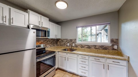 A kitchen with white cabinets and a granite countertop.