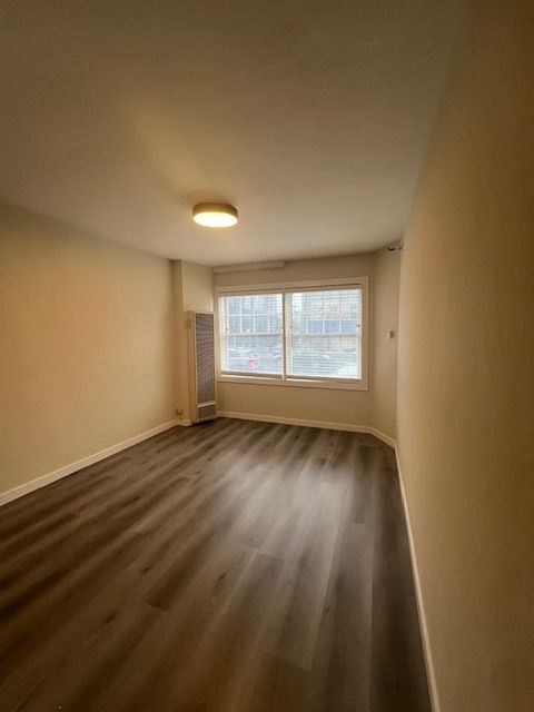 A room with a window and wooden flooring.