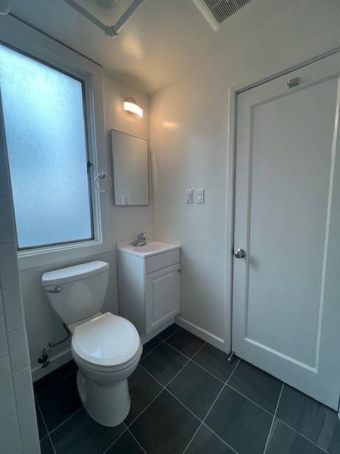 A white toilet sits next to a white cabinet in a bathroom.