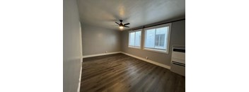 A room with a ceiling fan and wooden flooring.