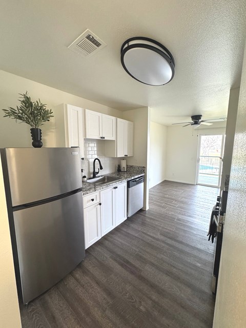 A modern kitchen with a stainless steel refrigerator and white cabinets.
