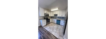 A kitchen with white cabinets and a black fridge.