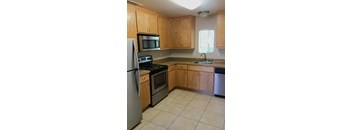 A kitchen with wooden cabinets and a stainless steel dishwasher.