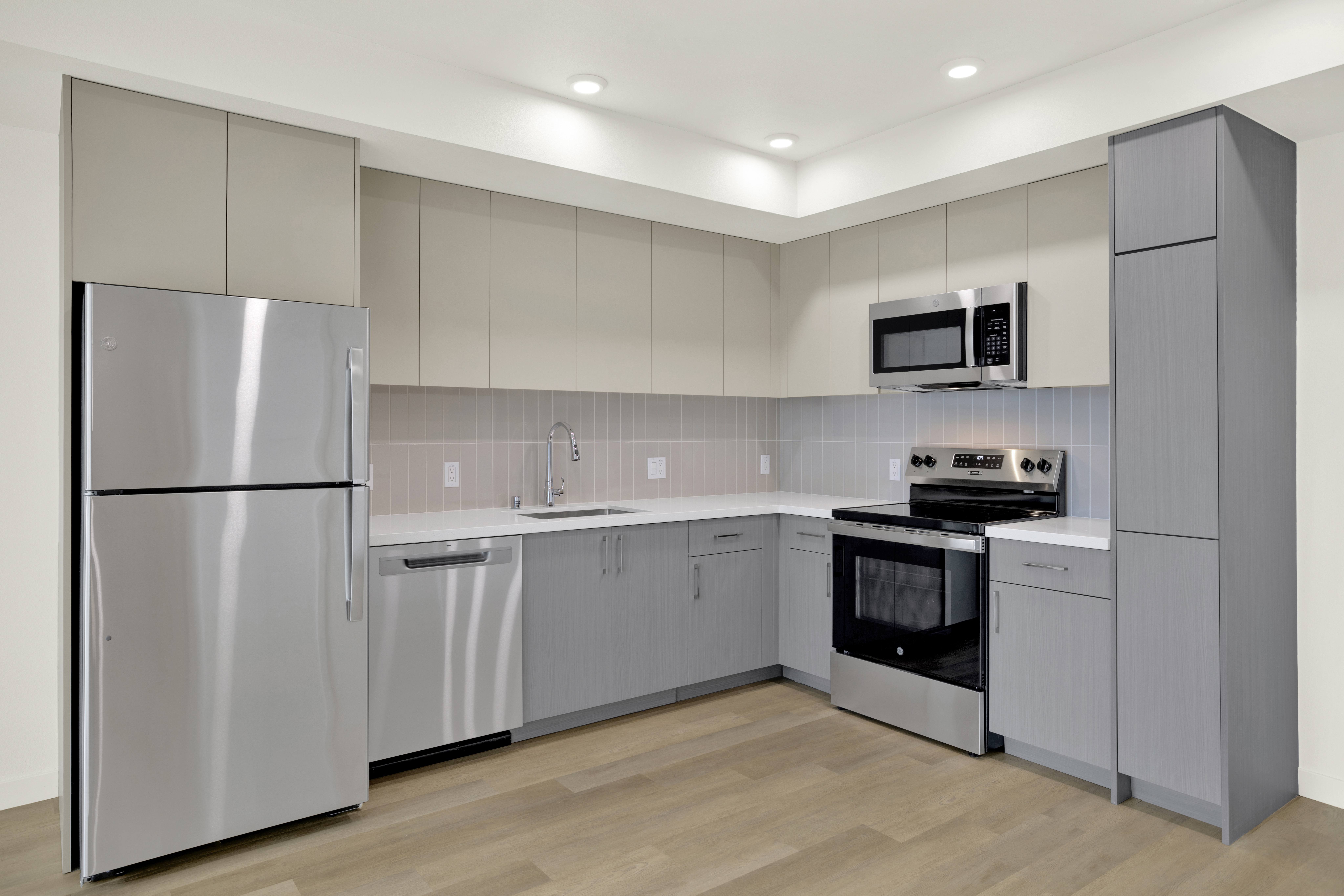 A modern kitchen with a stainless steel refrigerator and a microwave above the oven.