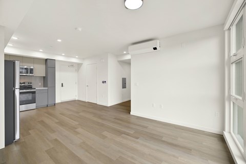 A spacious room with wooden flooring and white walls.